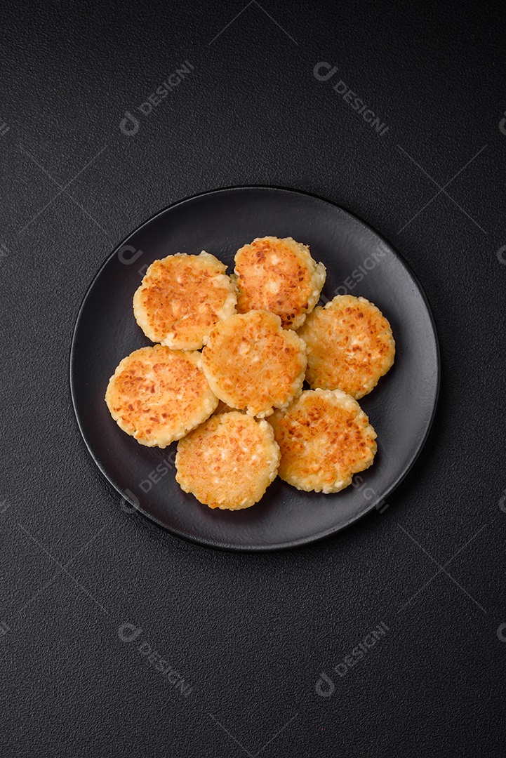 Deliciosos cheesecakes frescos com passas e baunilha em uma placa de cerâmica preta sobre um fundo escuro de concreto