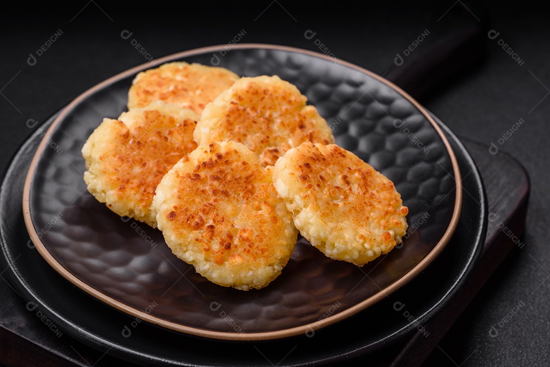 Deliciosos cheesecakes frescos com passas e baunilha em uma placa de cerâmica preta sobre um fundo escuro de concreto