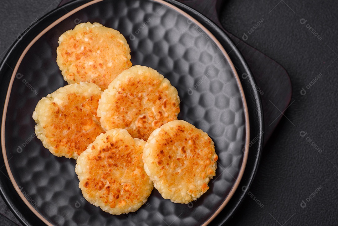 Deliciosos cheesecakes frescos com passas e baunilha em uma placa de cerâmica preta sobre um fundo escuro de concreto