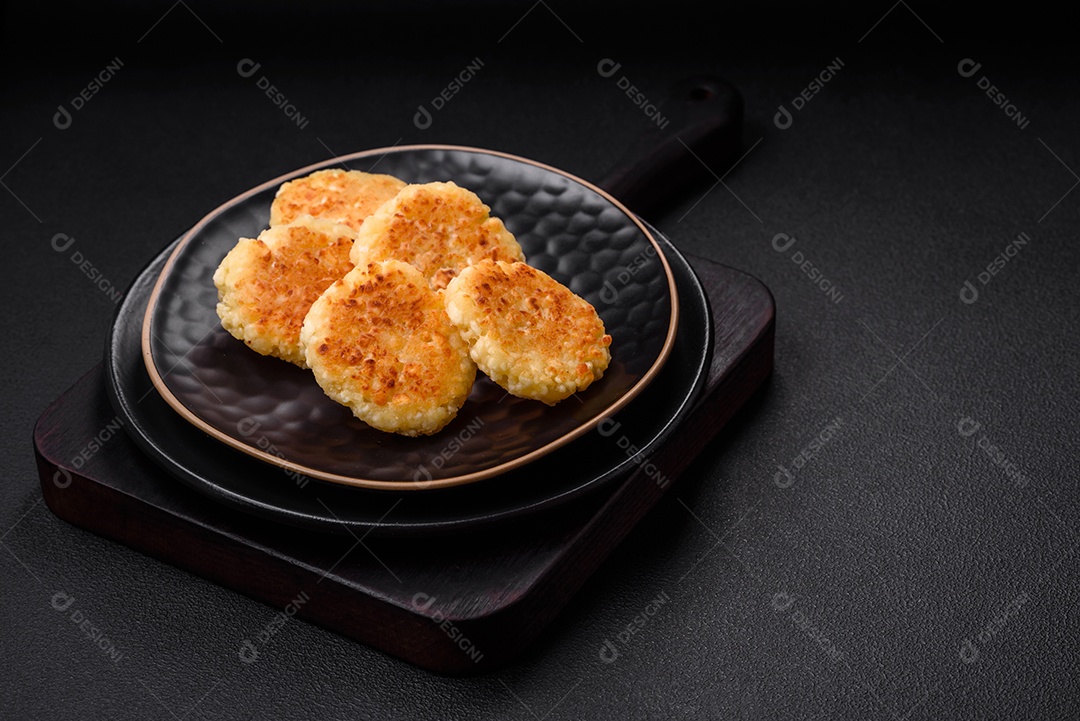 Deliciosos cheesecakes frescos com passas e baunilha em uma placa de cerâmica preta sobre um fundo escuro de concreto