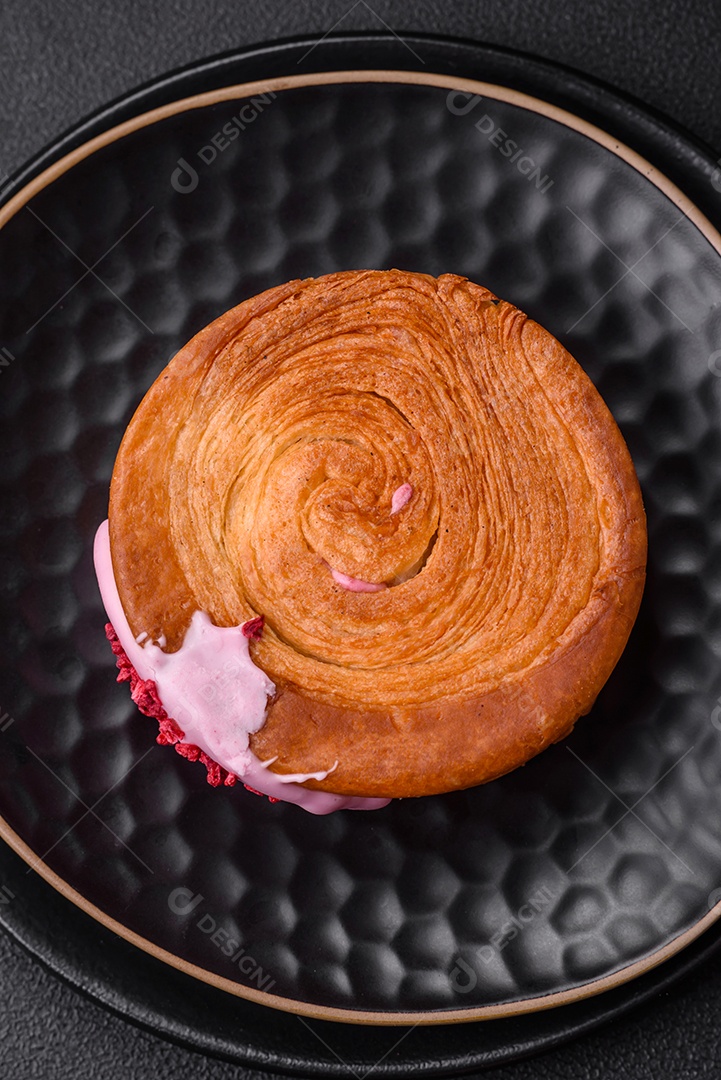 Croissant redondo de massa folhada com recheio de framboesa ou rolo de Nova Iorque sobre fundo escuro de concreto