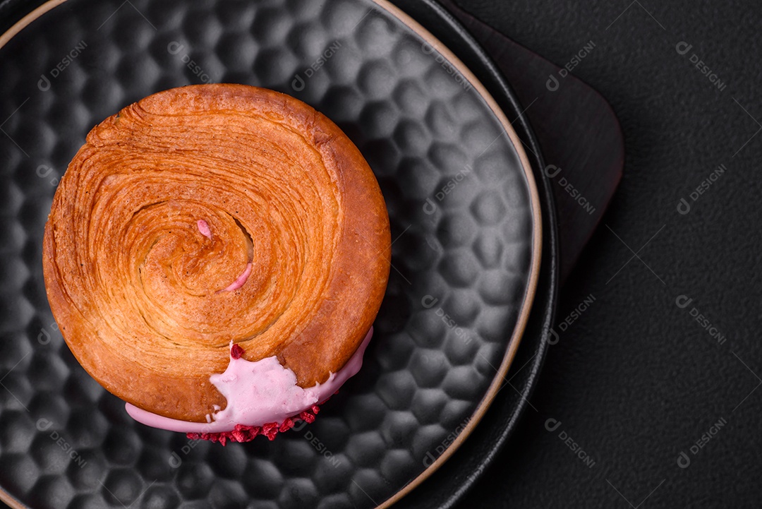 Croissant redondo de massa folhada com recheio de framboesa ou rolo de Nova Iorque sobre fundo escuro de concreto