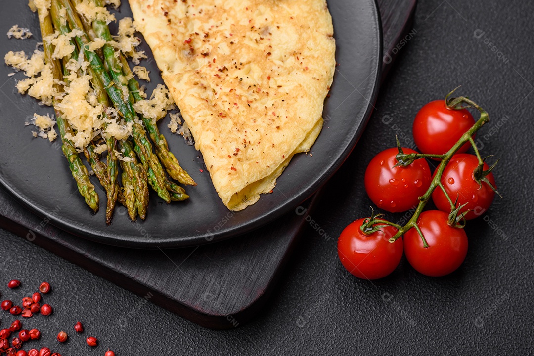 Delicioso café da manhã nutritivo composto por espargos, ovos mexidos, sal, especiarias e ervas sobre um fundo escuro de concreto
