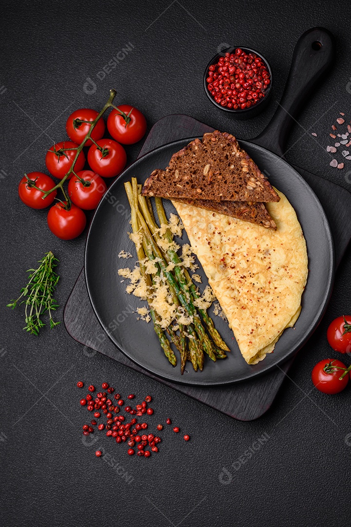 Delicioso café da manhã nutritivo composto por espargos, ovos mexidos, sal, especiarias e ervas sobre um fundo escuro de concreto