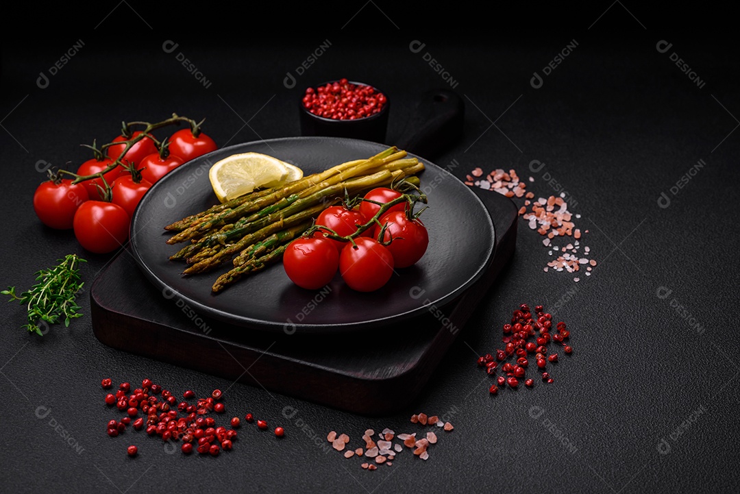 Delicioso café da manhã nutritivo composto por espargos, tomates, sal, especiarias e ervas sobre um fundo escuro de concreto