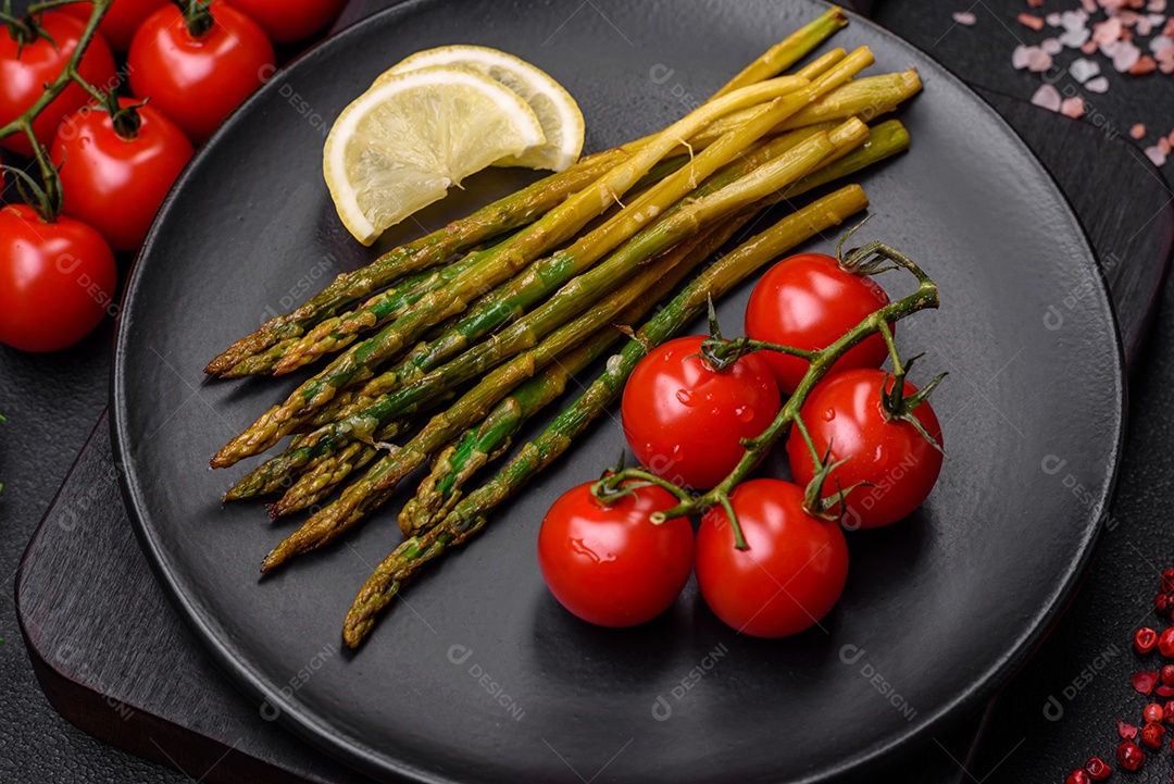 Delicioso café da manhã nutritivo composto por espargos, tomates, sal, especiarias e ervas sobre um fundo escuro de concreto