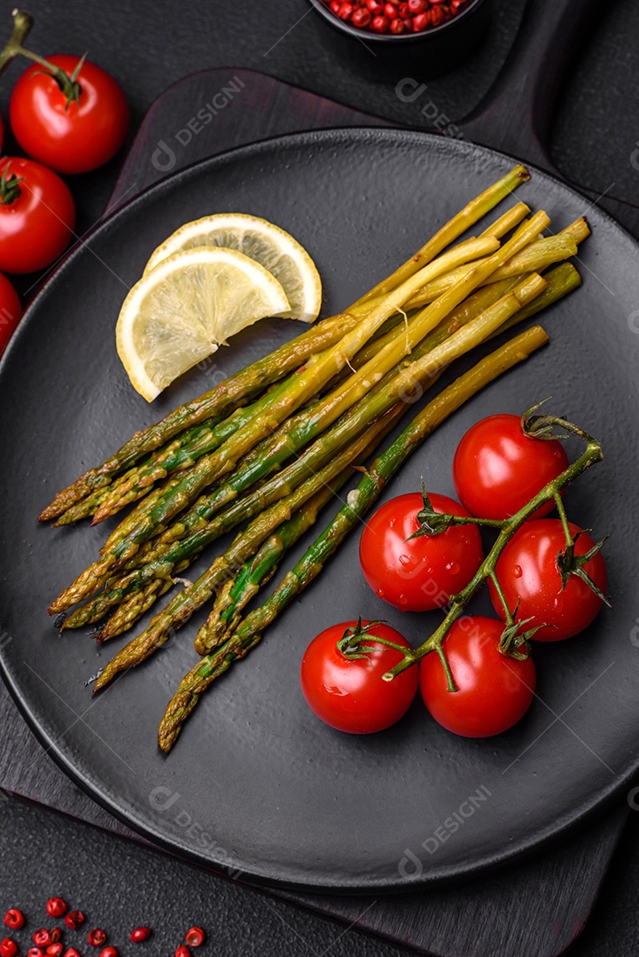 Delicioso café da manhã nutritivo composto por espargos, tomates, sal, especiarias e ervas sobre um fundo escuro de concreto