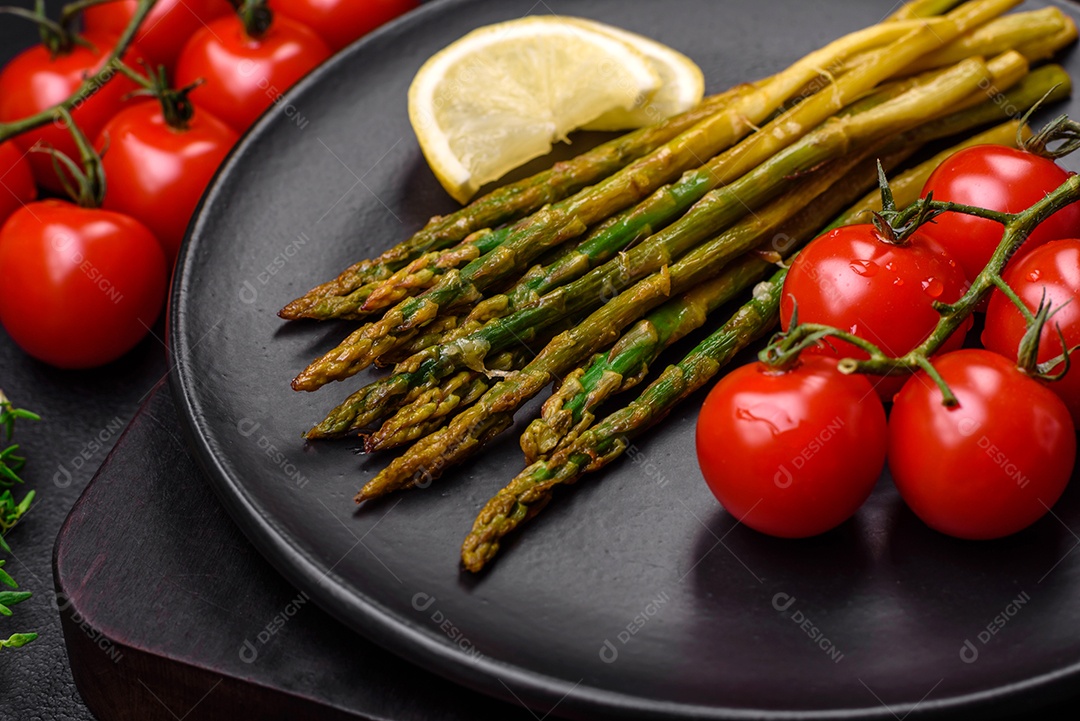 Delicioso café da manhã nutritivo composto por espargos, tomates, sal, especiarias e ervas sobre um fundo escuro de concreto