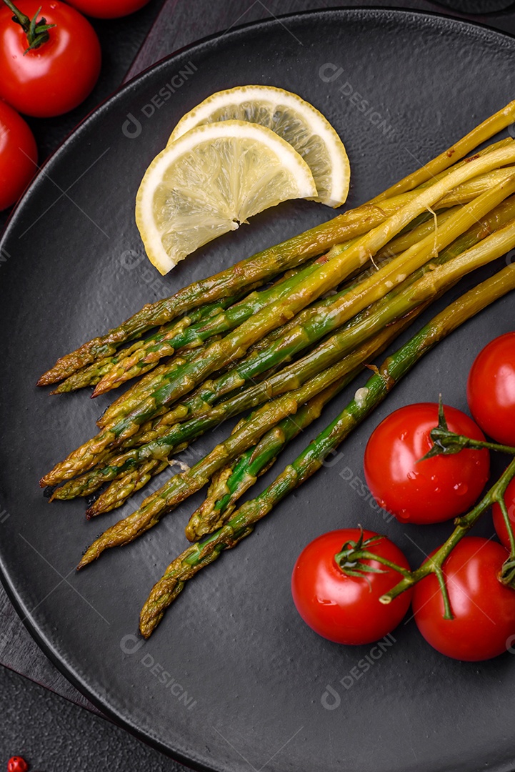 Delicioso café da manhã nutritivo composto por espargos, tomates, sal, especiarias e ervas sobre um fundo escuro de concreto