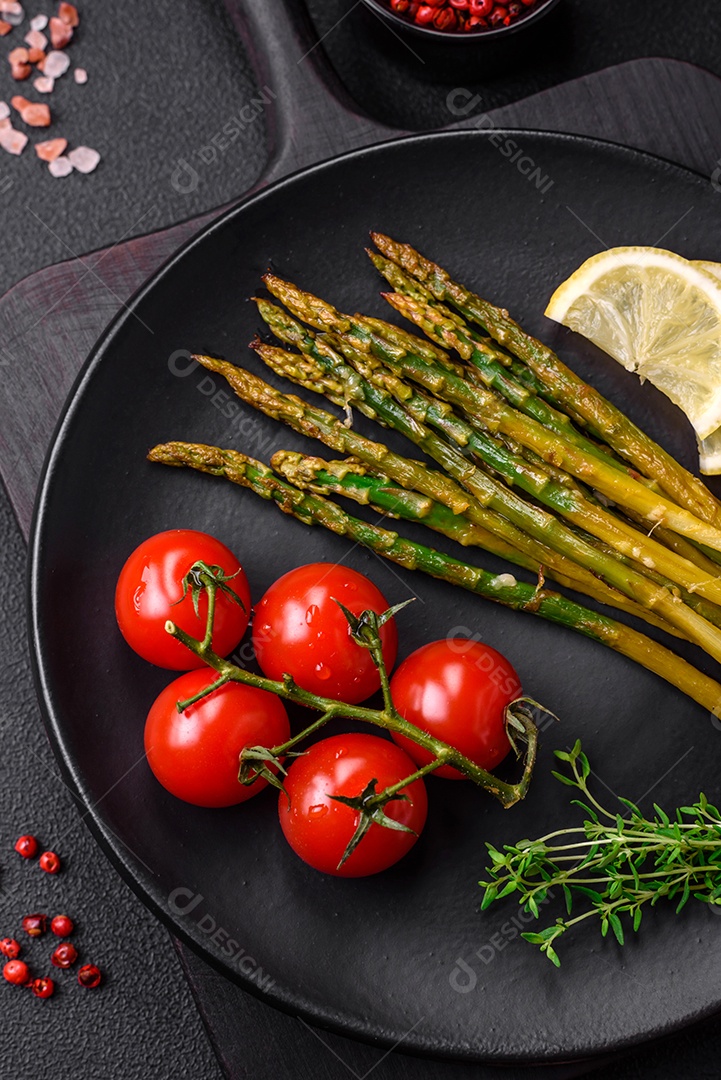 Delicioso café da manhã nutritivo composto por espargos, tomates, sal, especiarias e ervas sobre um fundo escuro de concreto