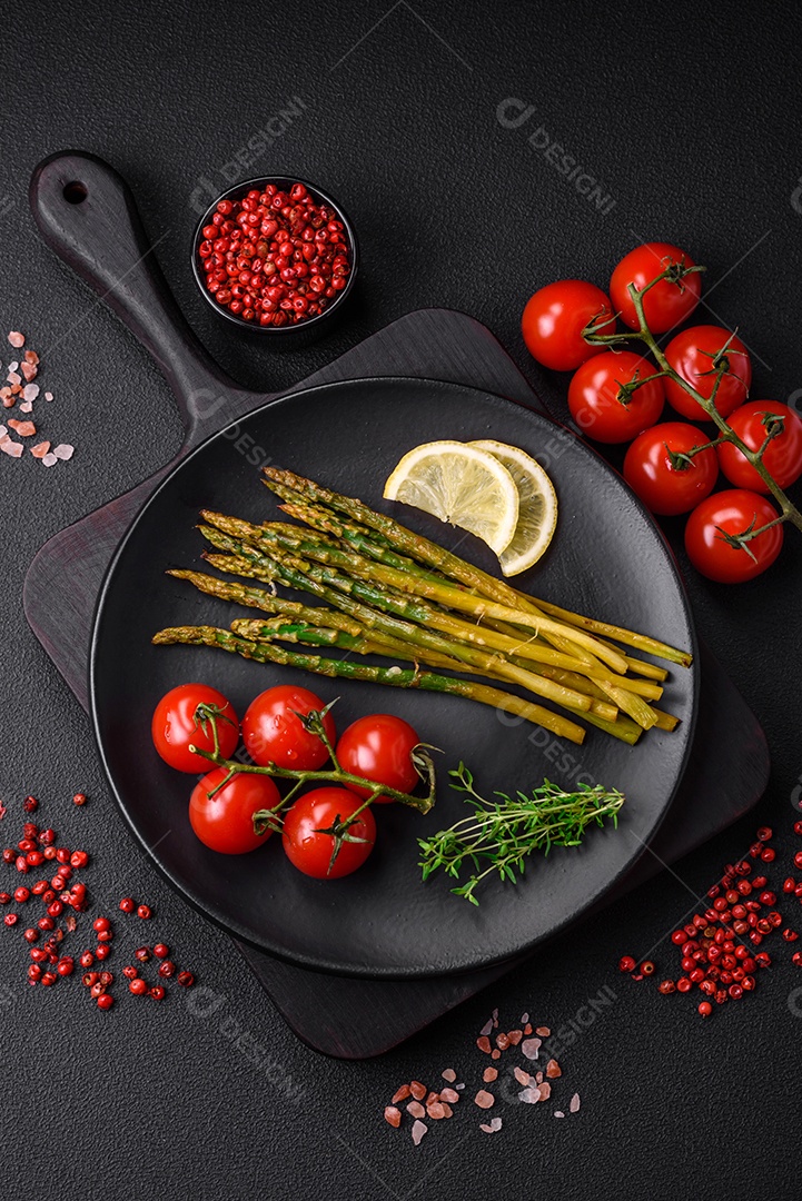 Delicioso café da manhã nutritivo composto por espargos, ovos mexidos, sal, especiarias e ervas sobre um fundo escuro de concreto