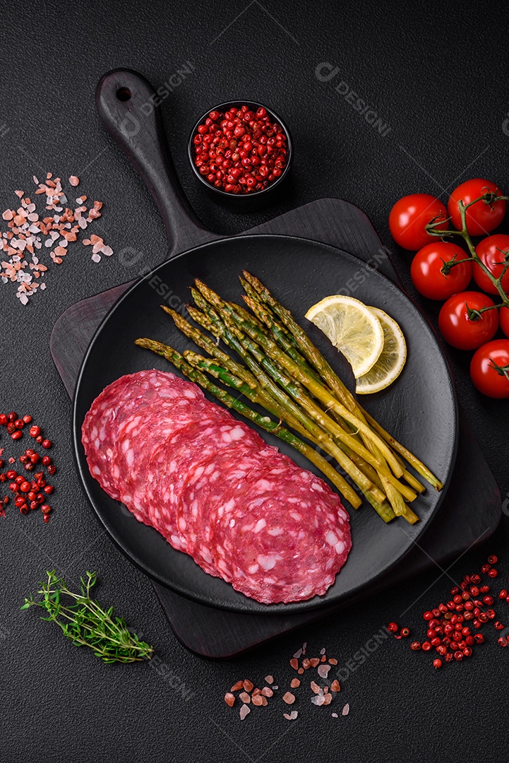 Delicioso café da manhã nutritivo composto por espargos, ovos mexidos, sal, especiarias e ervas sobre um fundo escuro de concreto