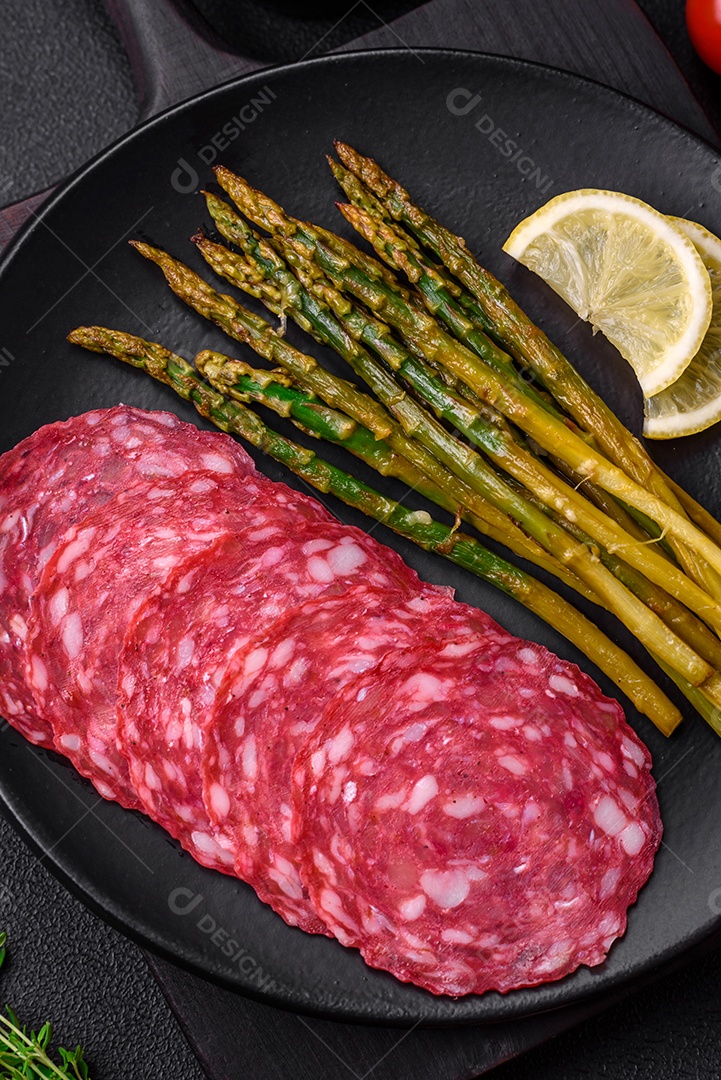 Delicioso café da manhã nutritivo composto por espargos, ovos mexidos, sal, especiarias e ervas sobre um fundo escuro de concreto
