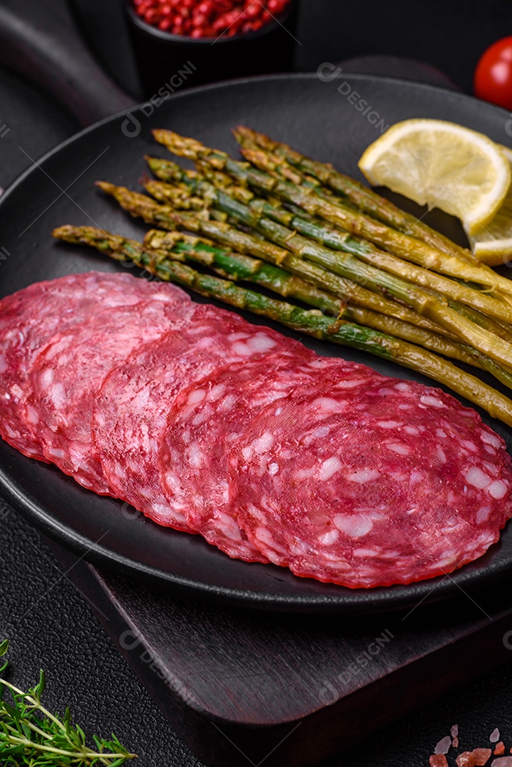 Delicioso café da manhã nutritivo composto por espargos, ovos mexidos, sal, especiarias e ervas sobre um fundo escuro de concreto