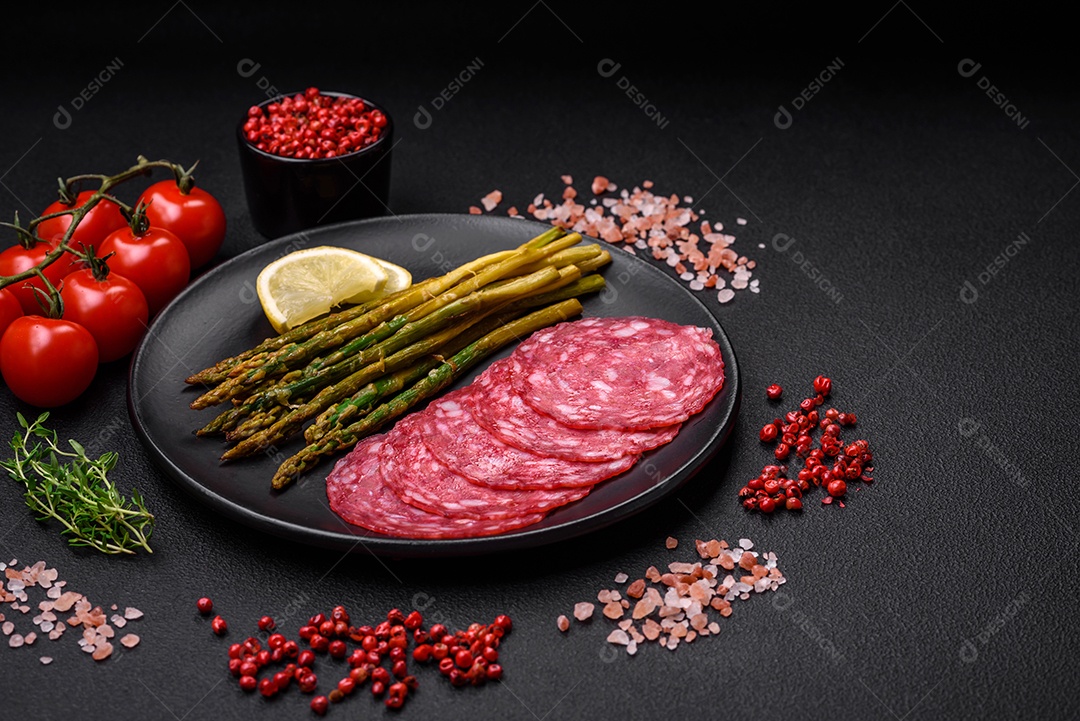 Delicioso café da manhã nutritivo composto por espargos, ovos mexidos, sal, especiarias e ervas sobre um fundo escuro de concreto