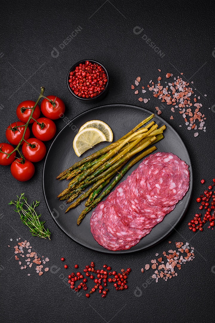 Delicioso café da manhã nutritivo composto por espargos, ovos mexidos, sal, especiarias e ervas sobre um fundo escuro de concreto