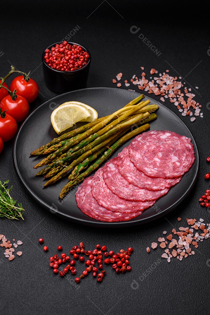 Delicioso café da manhã nutritivo composto por espargos, ovos mexidos, sal, especiarias e ervas sobre um fundo escuro de concreto