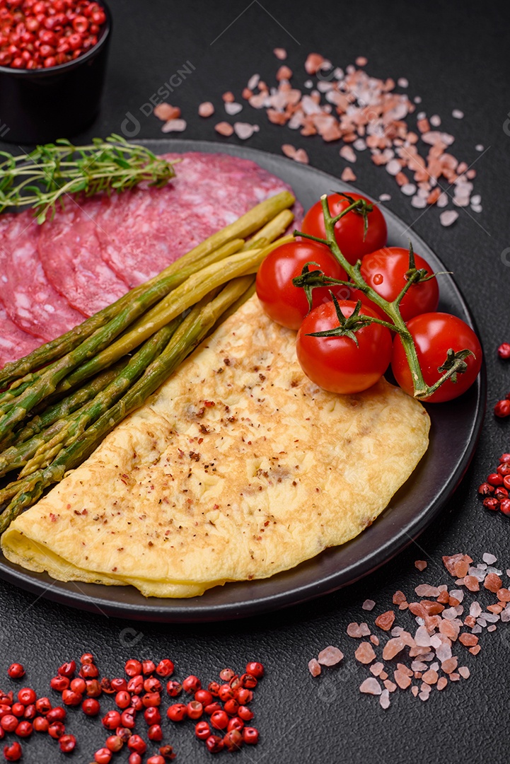 Delicioso café da manhã nutritivo composto por espargos, ovos mexidos, sal, especiarias e ervas sobre um fundo escuro de concreto