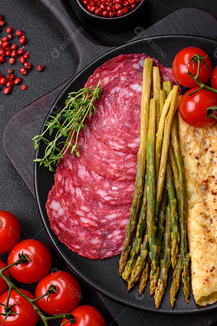 Delicioso café da manhã nutritivo composto por espargos, ovos mexidos, sal, especiarias e ervas sobre um fundo escuro de concreto