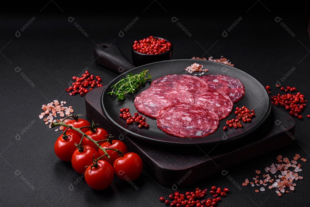 Delicioso café da manhã nutritivo composto por salsicha fatiada, espargos, sal, especiarias e ervas sobre um fundo escuro de concreto