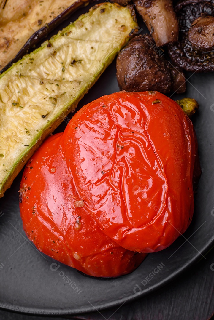 Deliciosos legumes grelhados, abobrinha, berinjela, pimentão e cogumelos com sal, especiarias e ervas sobre um fundo escuro de concreto