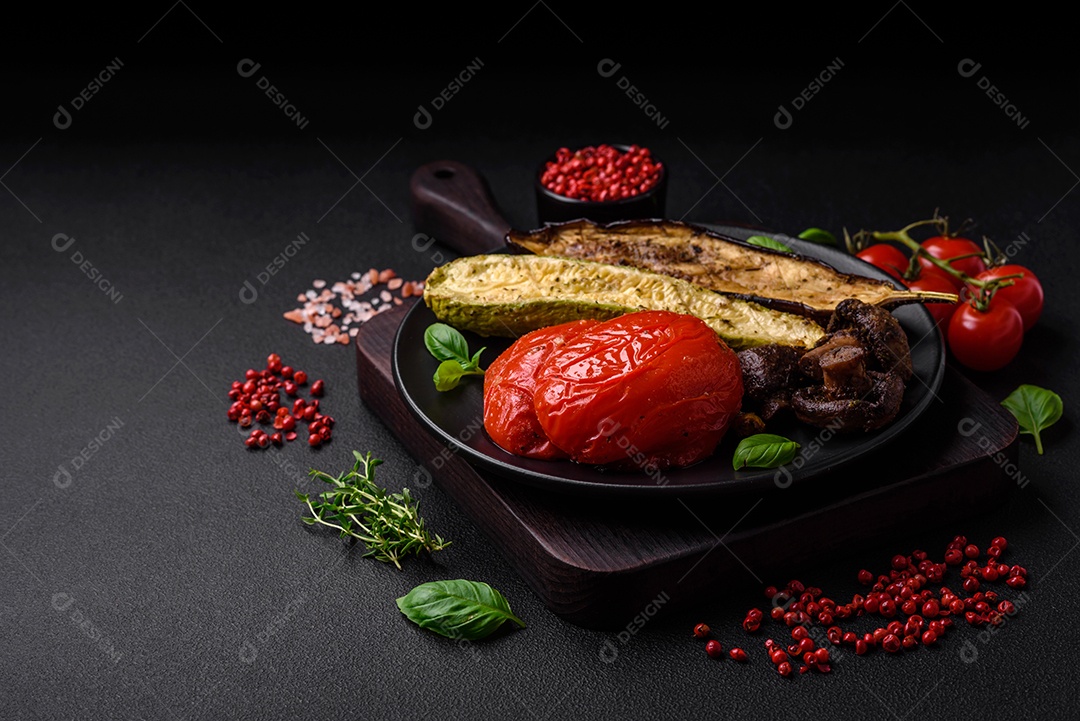 Deliciosos legumes grelhados, abobrinha, berinjela, pimentão e cogumelos com sal, especiarias e ervas sobre um fundo escuro de concreto