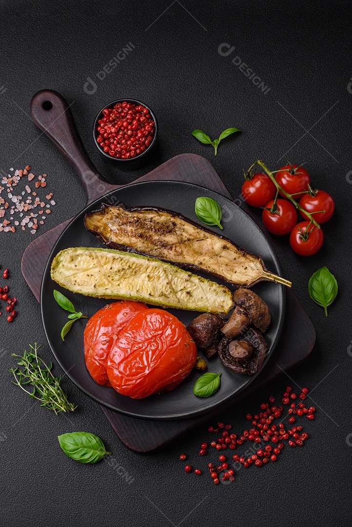 Deliciosos legumes grelhados, abobrinha, berinjela, pimentão e cogumelos com sal, especiarias e ervas sobre um fundo escuro de concreto