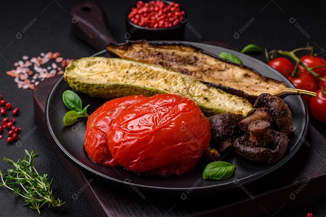 Deliciosos legumes grelhados, abobrinha, berinjela, pimentão e cogumelos com sal, especiarias e ervas sobre um fundo escuro de concreto