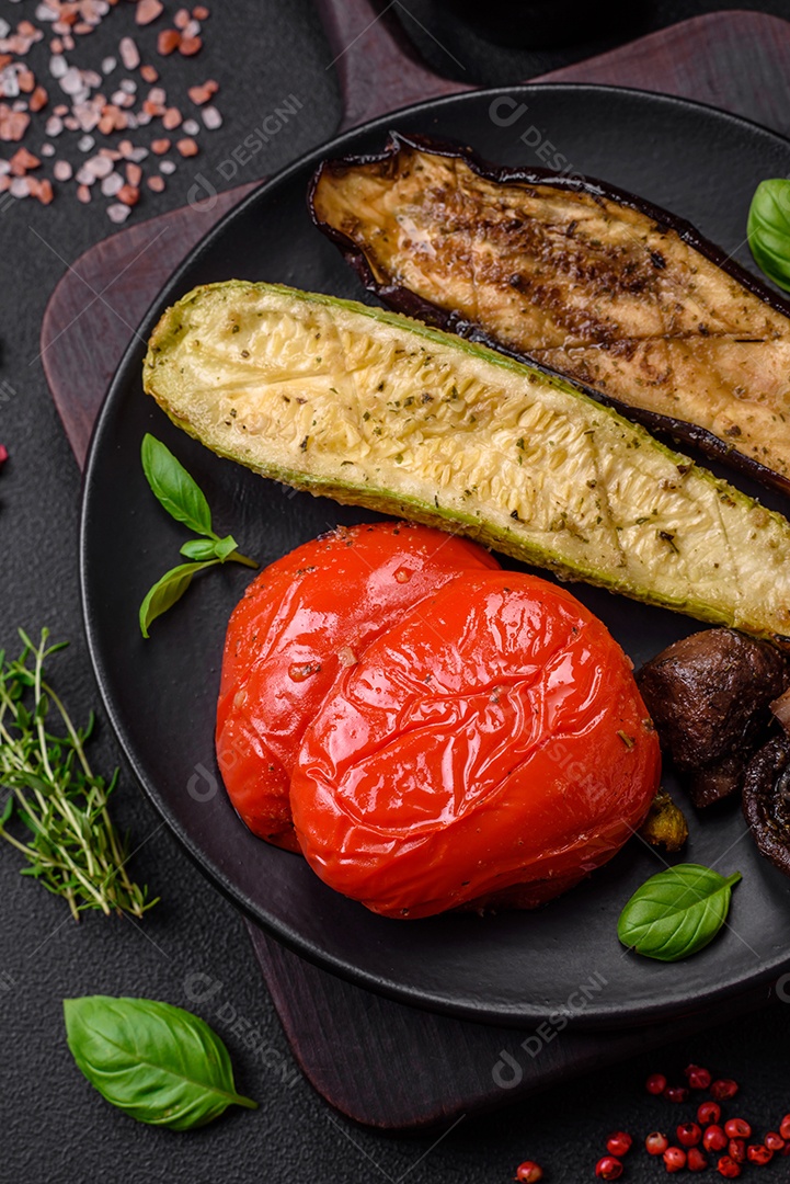 Deliciosos legumes grelhados, abobrinha, berinjela, pimentão e cogumelos com sal, especiarias e ervas sobre um fundo escuro de concreto