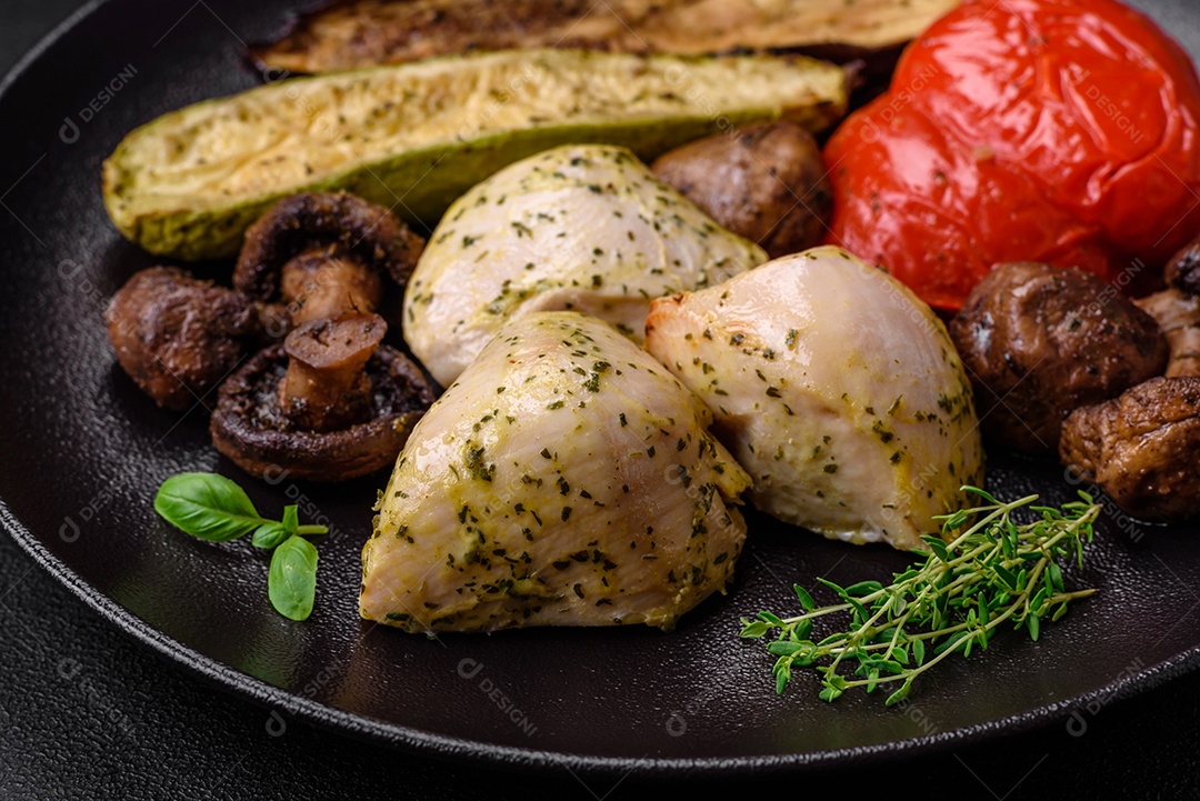 Delicioso suculento frango grelhado com sal, especiarias e ervas com legumes em um fundo escuro de concreto