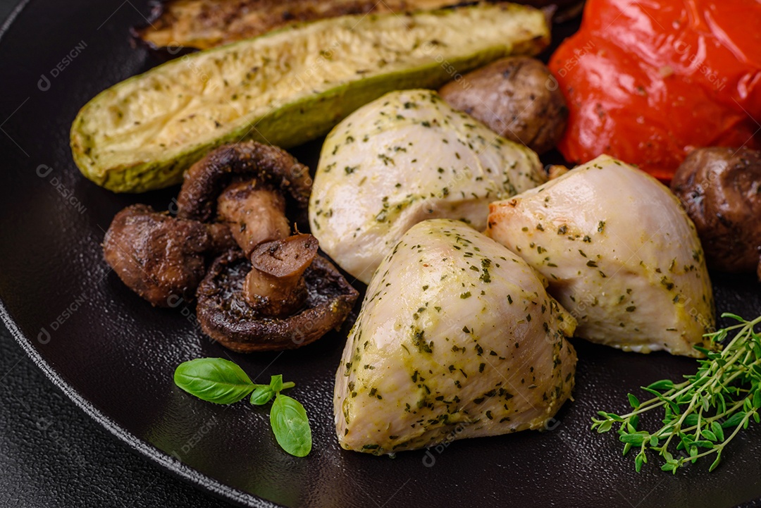 Delicioso suculento frango grelhado com sal, especiarias e ervas com legumes em um fundo escuro de concreto