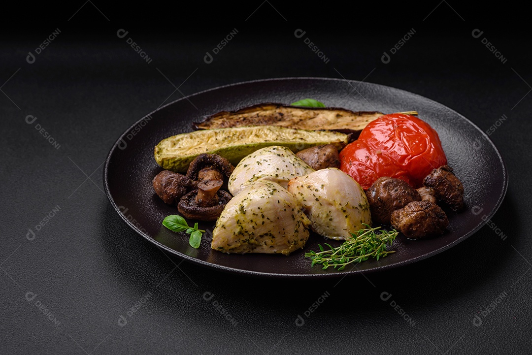 Delicioso suculento frango grelhado com sal, especiarias e ervas com legumes em um fundo escuro de concreto