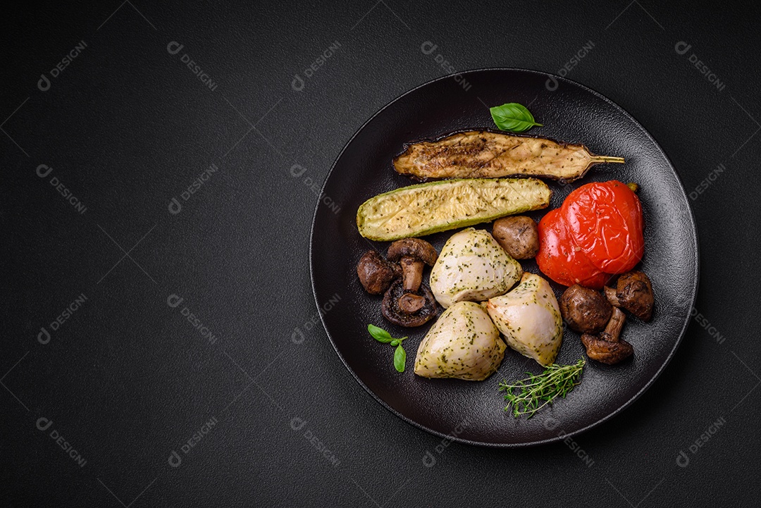 Delicioso suculento frango grelhado com sal, especiarias e ervas com legumes em um fundo escuro de concreto