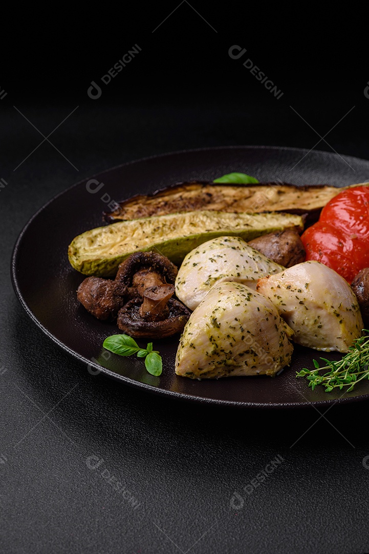 Delicioso suculento frango grelhado com sal, especiarias e ervas com legumes em um fundo escuro de concreto