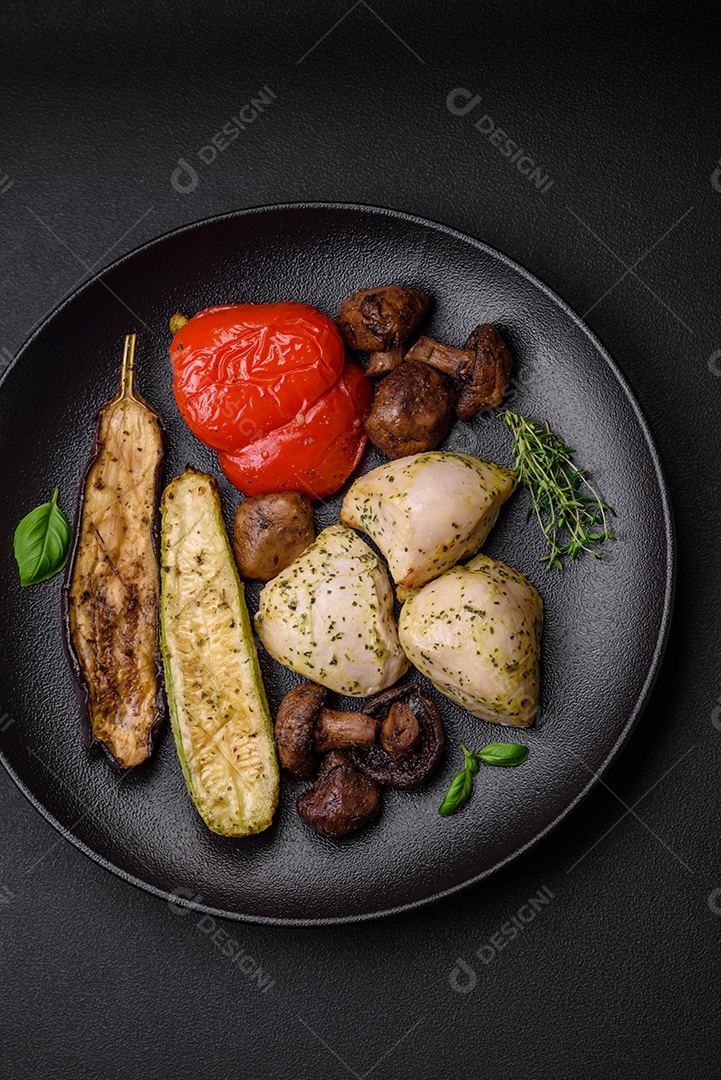 Delicioso suculento frango grelhado com sal, especiarias e ervas com legumes em um fundo escuro de concreto