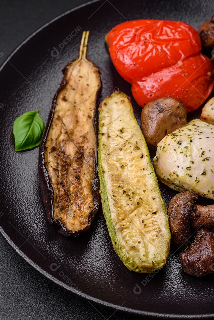 Deliciosos legumes grelhados, abobrinha, berinjela, pimentão e cogumelos com sal, especiarias e ervas sobre um fundo escuro de concreto