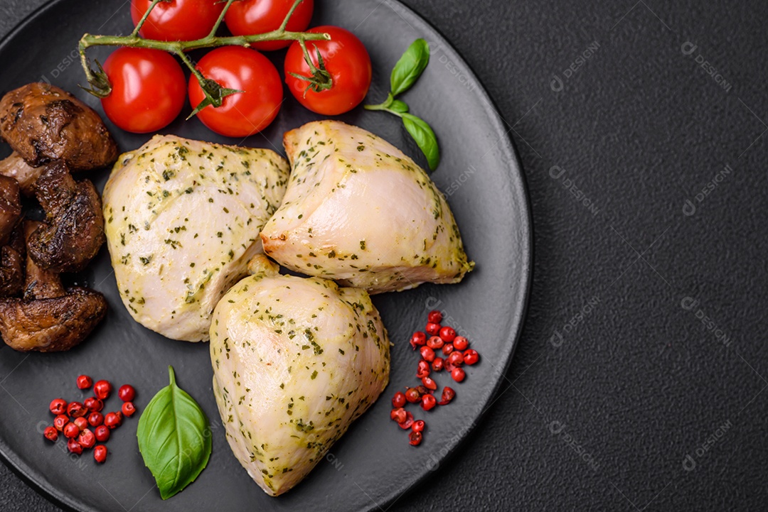 Delicioso suculento frango grelhado com sal, especiarias e ervas com legumes em um fundo escuro de concreto