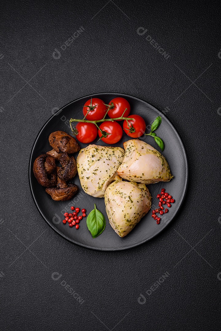 Delicioso suculento frango grelhado com sal, especiarias e ervas com legumes em um fundo escuro de concreto