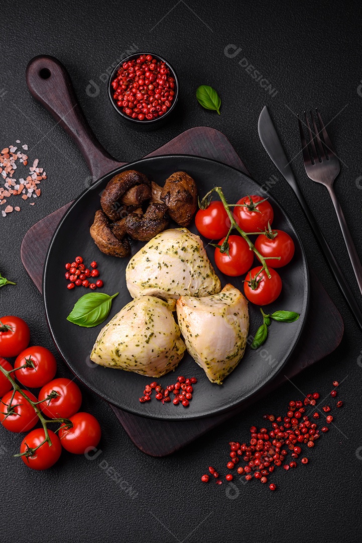 Delicioso suculento frango grelhado com sal, especiarias e ervas com legumes em um fundo escuro de concreto