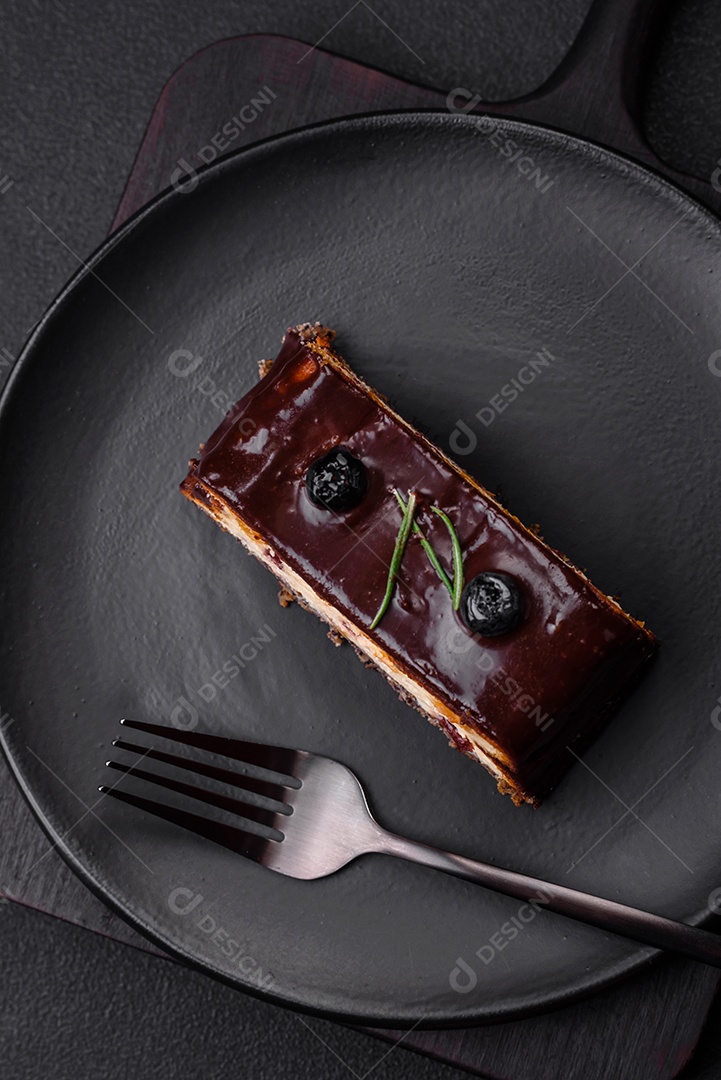 Delicioso cheesecake de sobremesa doce com frutas cristalizadas em chocolate sobre um fundo escuro de concreto