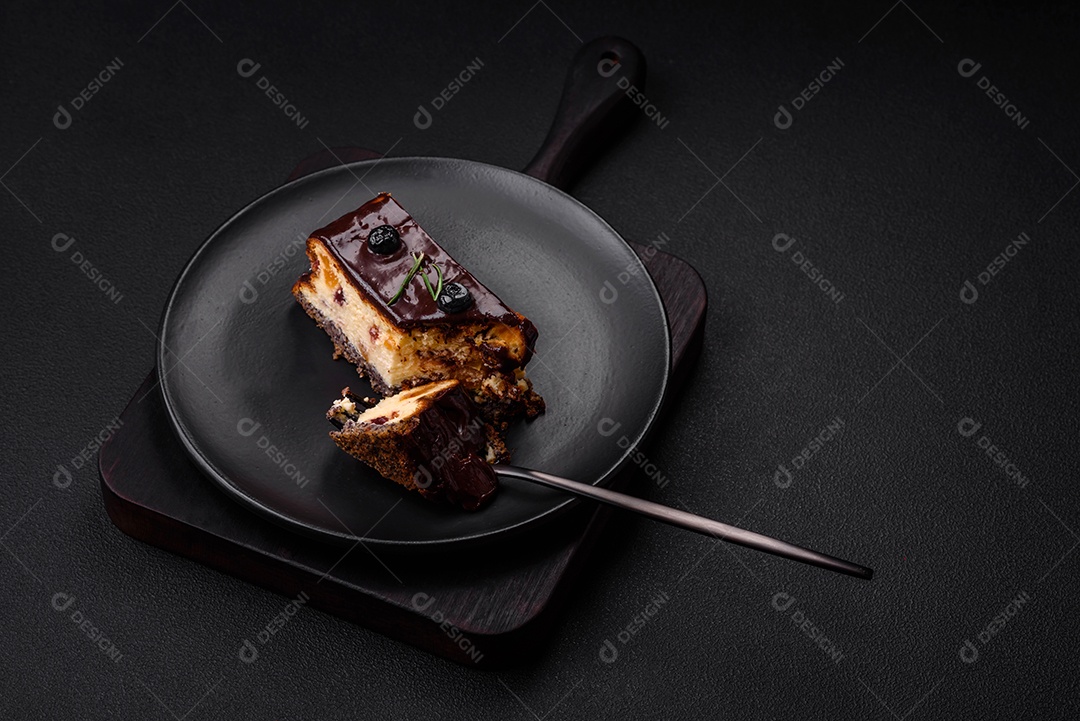 Delicioso cheesecake de sobremesa doce com frutas cristalizadas em chocolate sobre um fundo escuro de concreto