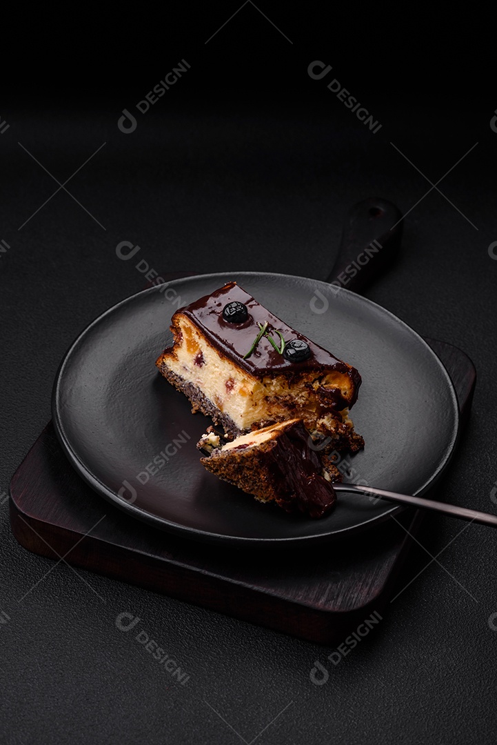 Delicioso cheesecake de sobremesa doce com frutas cristalizadas em chocolate sobre um fundo escuro de concreto