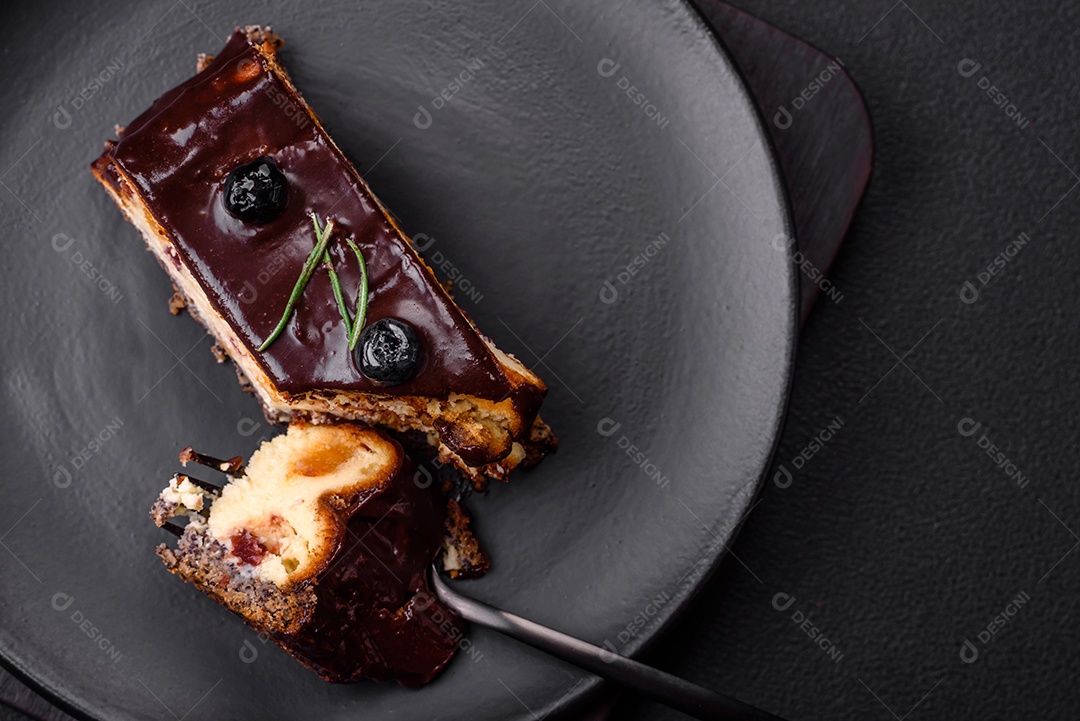 Delicioso cheesecake de sobremesa doce com frutas cristalizadas em chocolate sobre um fundo escuro de concreto