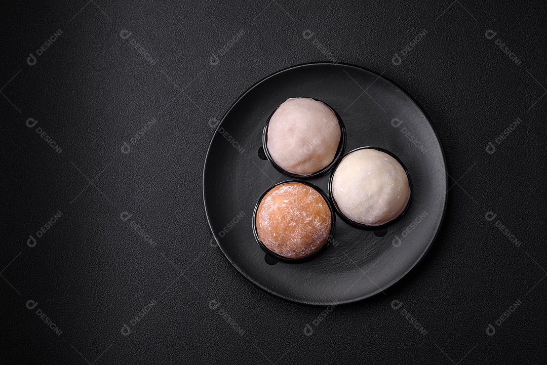 Deliciosa sobremesa mochi doce com coberturas em um fundo escuro de concreto. Sobremesa asiática vegetariana nutritiva