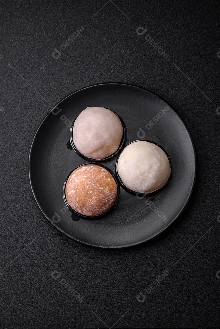 Deliciosa sobremesa mochi doce com coberturas em um fundo escuro de concreto. Sobremesa asiática vegetariana nutritiva