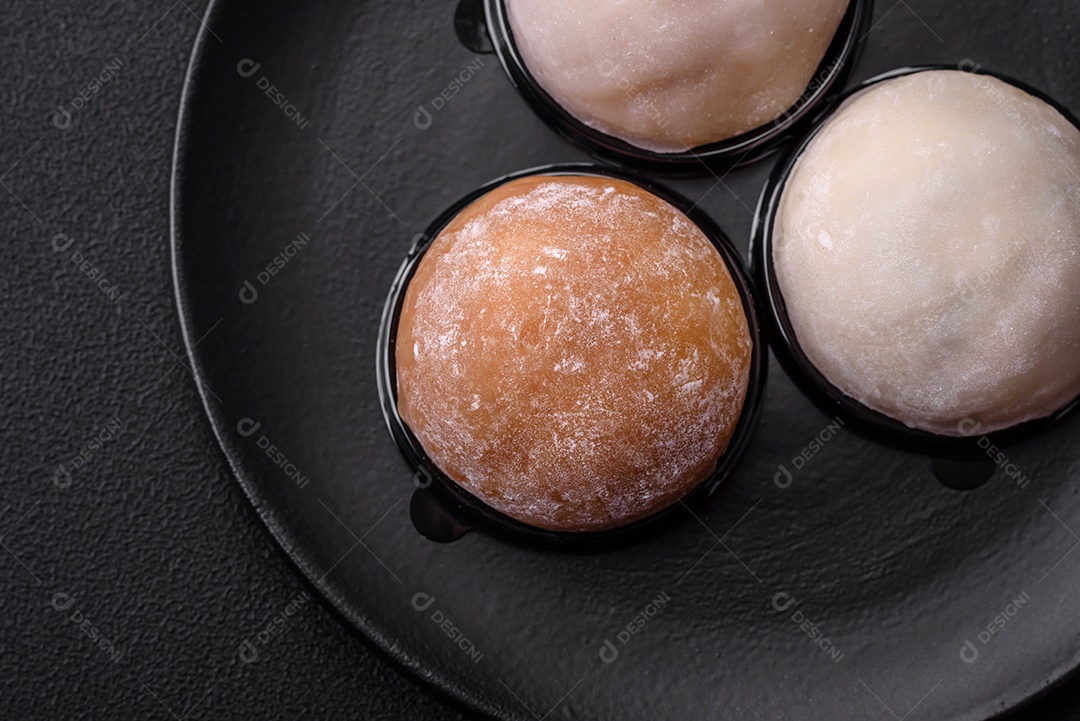 Deliciosa sobremesa mochi doce com coberturas em um fundo escuro de concreto. Sobremesa asiática vegetariana nutritiva