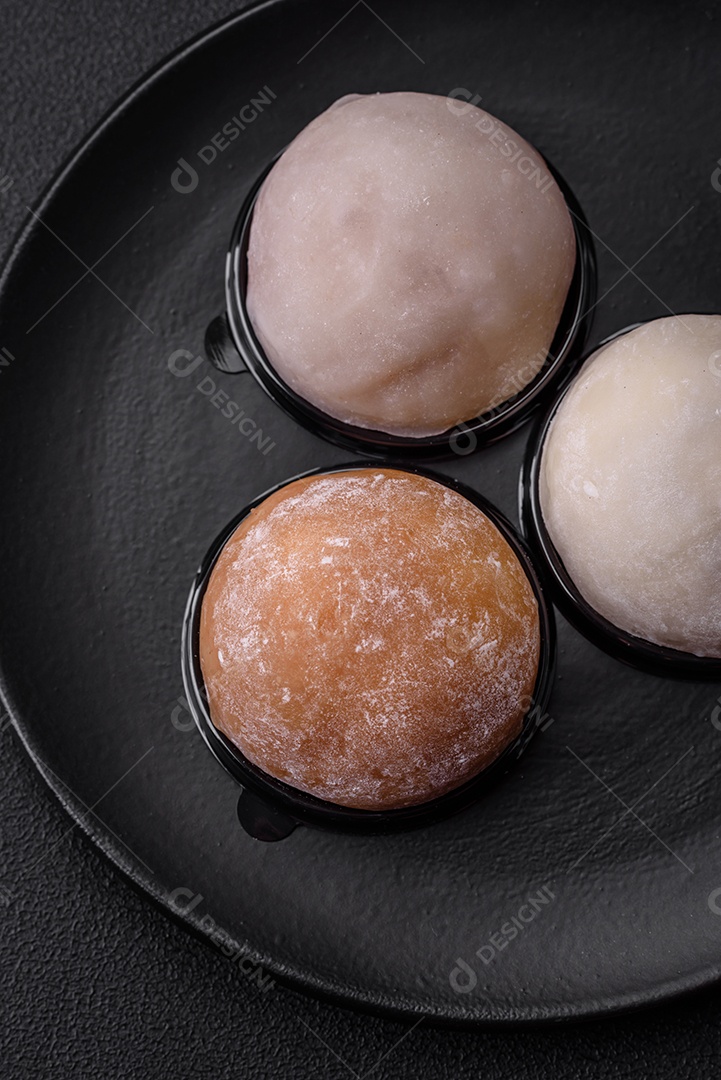 Deliciosa sobremesa mochi doce com coberturas em um fundo escuro de concreto. Sobremesa asiática vegetariana nutritiva