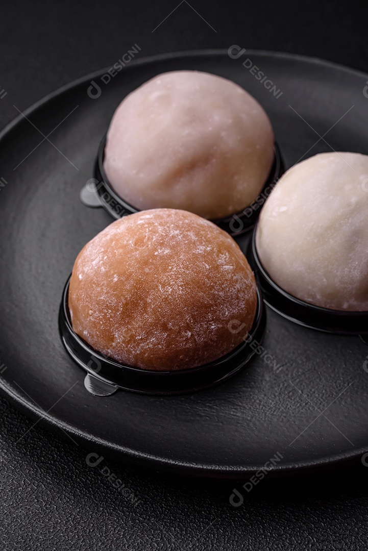 Deliciosa sobremesa mochi doce com coberturas em um fundo escuro de concreto. Sobremesa asiática vegetariana nutritiva