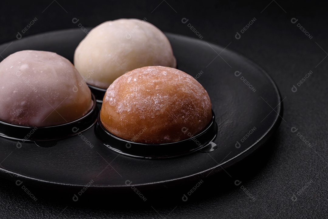 Deliciosa sobremesa mochi doce com coberturas em um fundo escuro de concreto. Sobremesa asiática vegetariana nutritiva