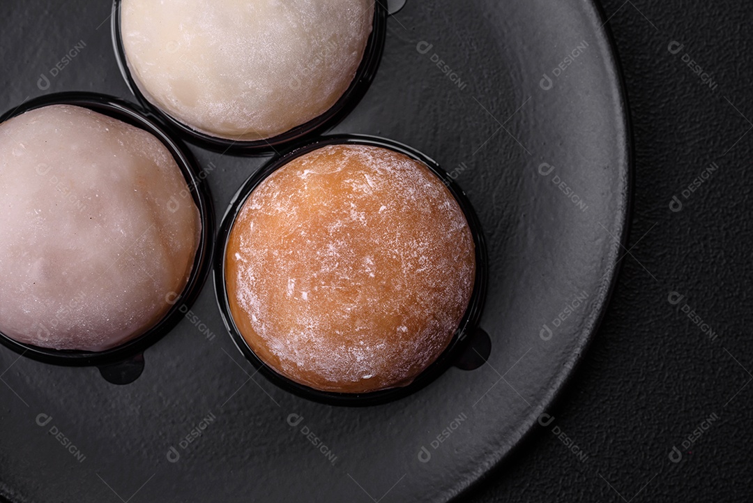 Deliciosa sobremesa mochi doce com coberturas em um fundo escuro de concreto. Sobremesa asiática vegetariana nutritiva